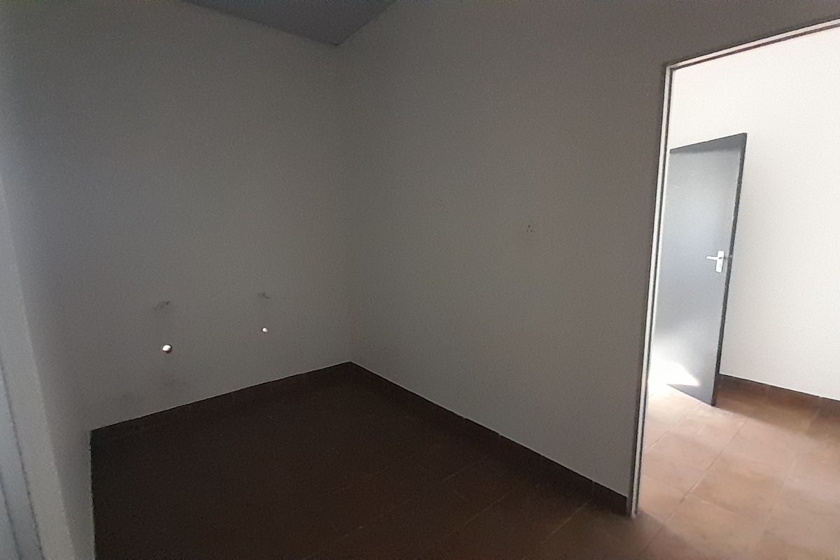 An empty utility or service room featuring tiled flooring and visible plumbing connections, providing a functional space for laundry or storage needs.