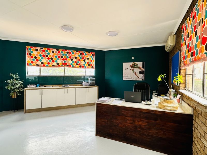 A well-maintained office space featuring dark green walls, exposed brick accents, built-in storage cabinetry, and a split-system air conditioning unit.