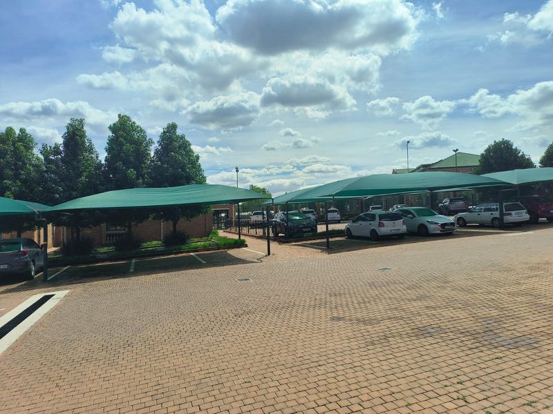 A paved office parking area featuring multiple shade cloth carports and secure perimeter fencing.