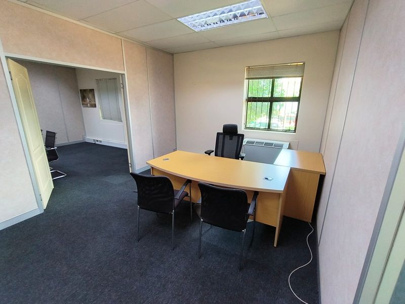 A functional office space featuring partition walls, carpet flooring, recessed lighting, and an integrated HVAC unit, providing a practical work environment.