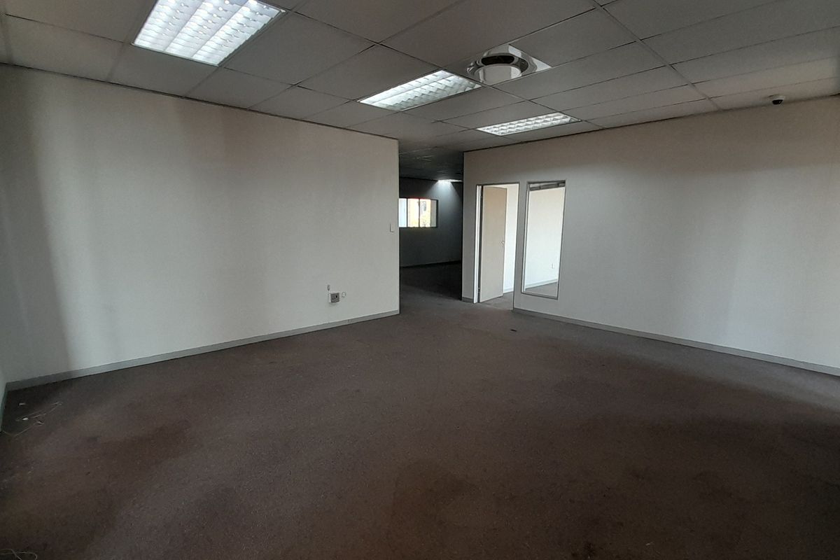 An empty, open-plan office space featuring a suspended ceiling with recessed lighting and carpeted flooring, offering a blank canvas for professional fit-out.