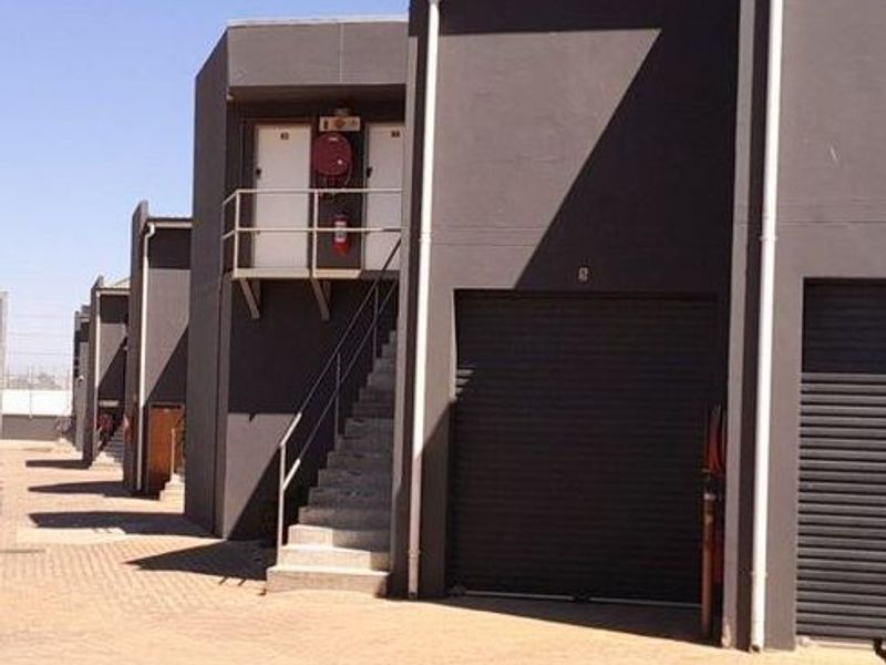 Industrial complex featuring multiple units with roller shutter doors, external staircases, and paved access areas.