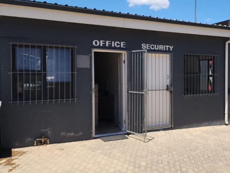 Industrial office and security entrance featuring a paved exterior area, secure metal gates, and protective window bars.