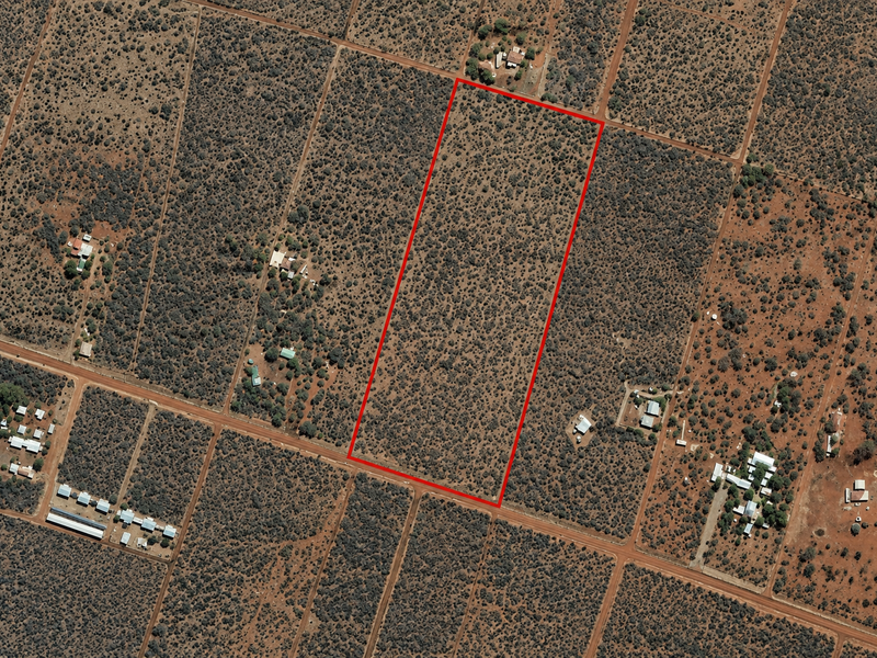 An aerial view of a large, undeveloped rectangular plot of land in a rural farm setting, clearly outlined in red.
