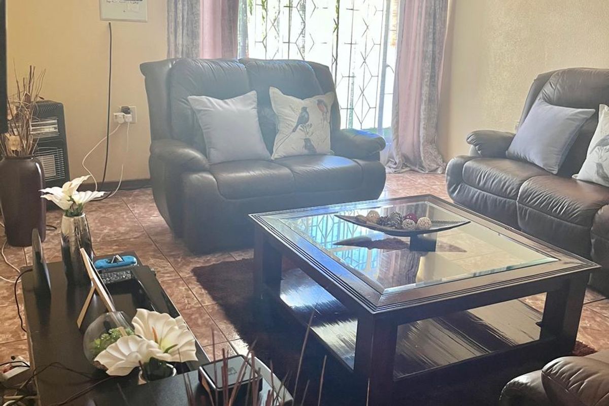 A comfortable living room featuring tiled flooring and a security gate over the window, providing a functional and secure living space.