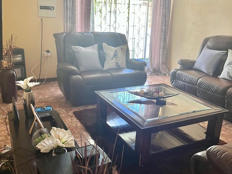 A comfortable living room featuring tiled flooring and a security gate over the window, providing a functional and secure living space.