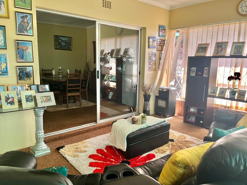 Open plan living and dining area featuring sliding glass doors, carpeted flooring, and natural light through vertical blinds.