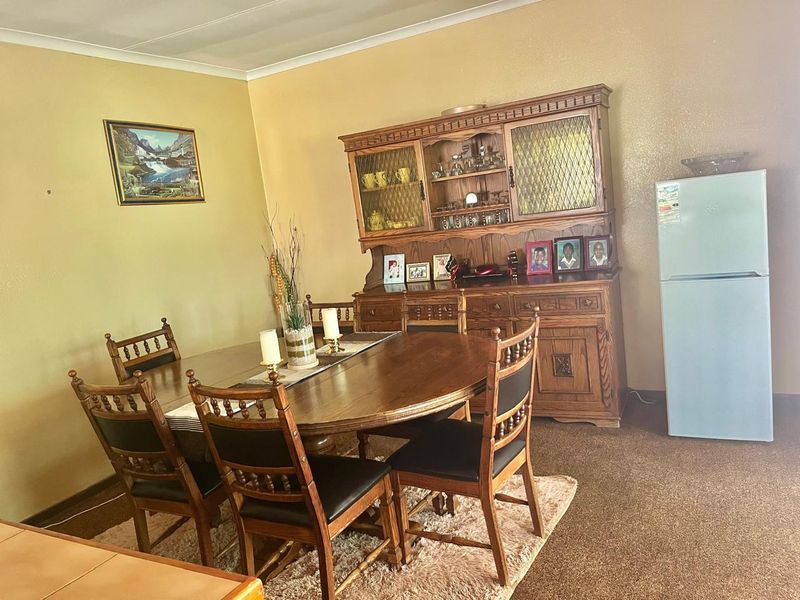 A traditional dining room featuring carpeted flooring and coved ceiling details, providing a functional space for family meals.
