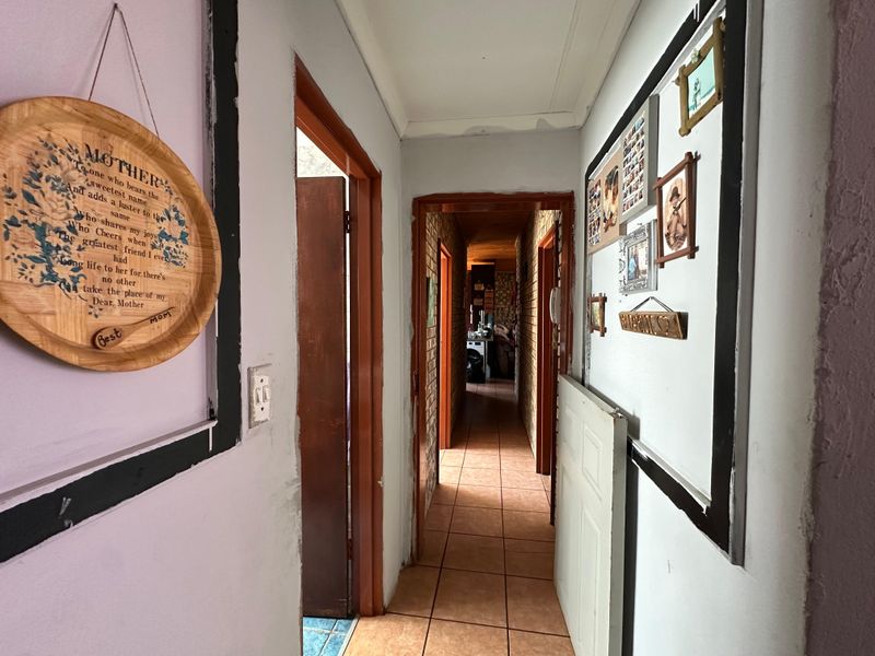 A narrow interior hallway featuring tiled flooring and wooden door frames, connecting multiple rooms within the property.