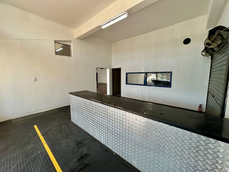 A functional utility or retail service space featuring a built-in metal-clad counter, durable rubber flooring, and industrial-style lighting.