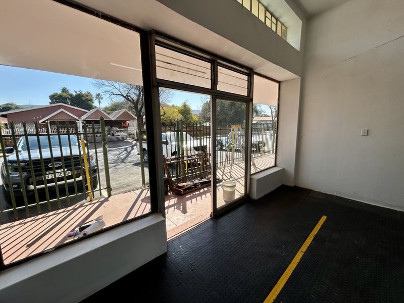 Bright retail entry space featuring large glass storefront windows, sliding door access, and durable rubberized flooring, suitable for a variety of commercial uses.