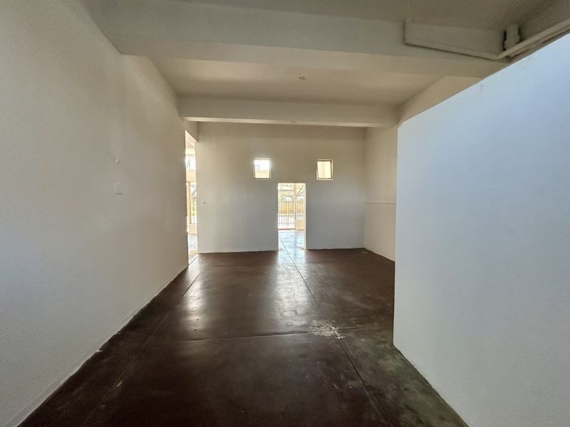 An empty, open-plan retail space featuring exposed ceiling beams and durable concrete flooring, offering a blank canvas for custom commercial fit-outs.