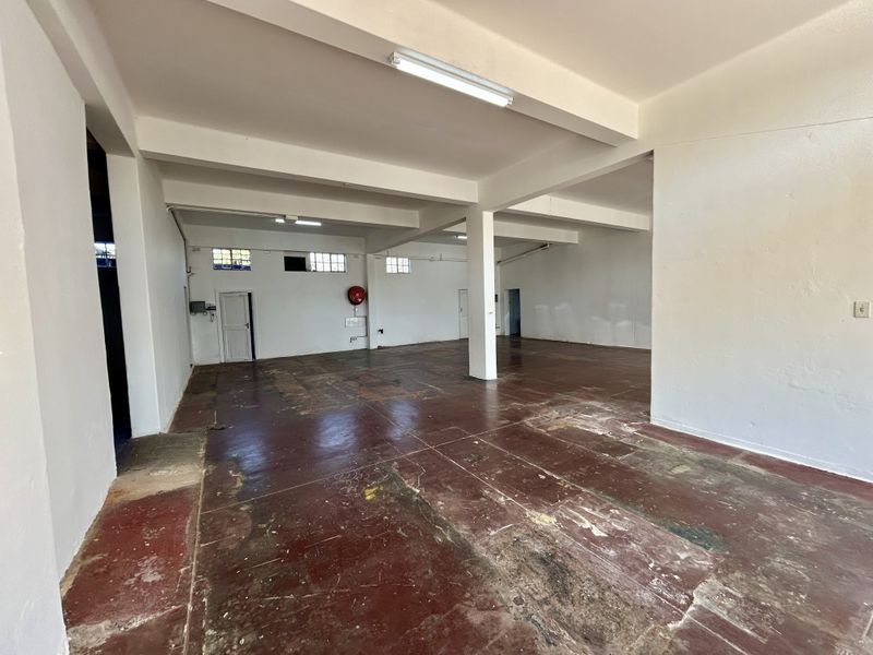 Spacious open-plan retail area featuring concrete flooring, support columns, and functional overhead lighting, suitable for various commercial or retail business applications.