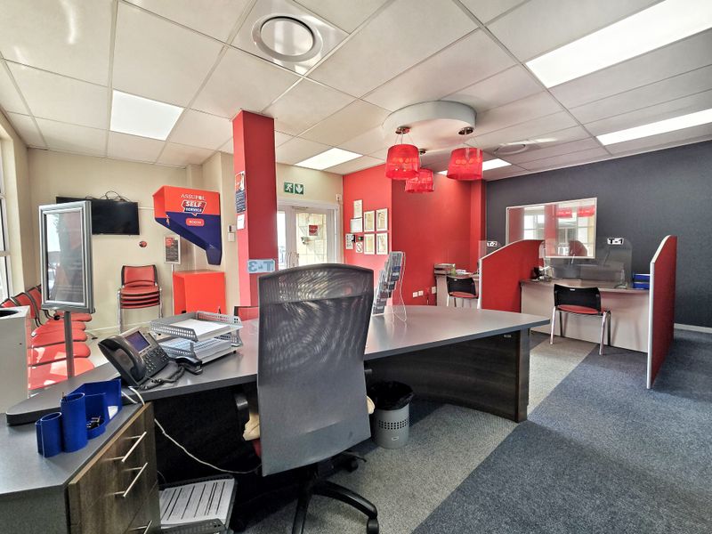A functional office space featuring built-in service counters, partitioned workstations, suspended ceilings with recessed lighting, and carpeted flooring.
