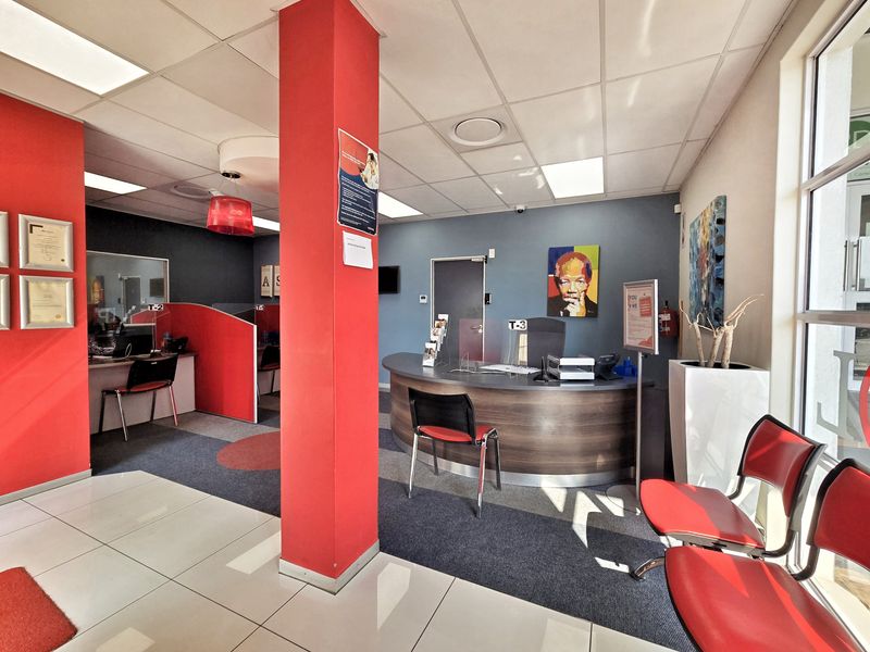 A professional office reception area featuring a curved service desk, partitioned workstations, and a mix of tiled and carpeted flooring.