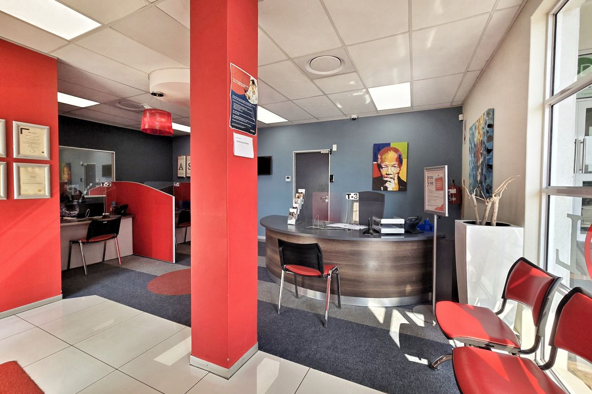 A professional office reception area featuring a curved service desk, partitioned workstations, and a mix of tiled and carpeted flooring.
