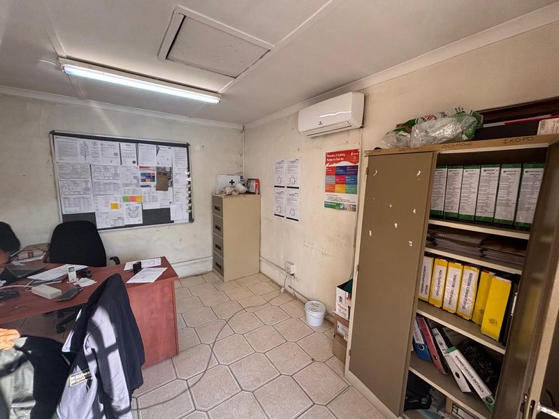A functional office space featuring tiled flooring, wall-mounted air conditioning, and built-in storage, currently utilized for administrative tasks and document filing.