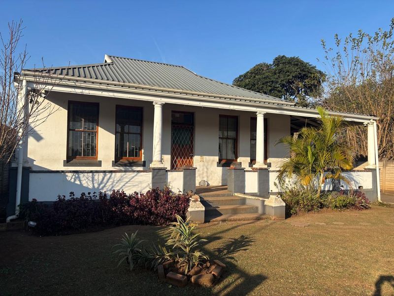 A charming office building featuring a covered veranda with classical columns, timber-framed windows, and a durable corrugated metal roof.