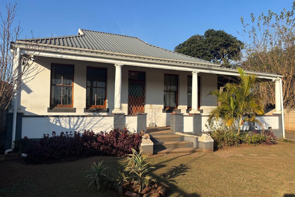 A charming office building featuring a covered veranda with classical columns, timber-framed windows, and a durable corrugated metal roof.