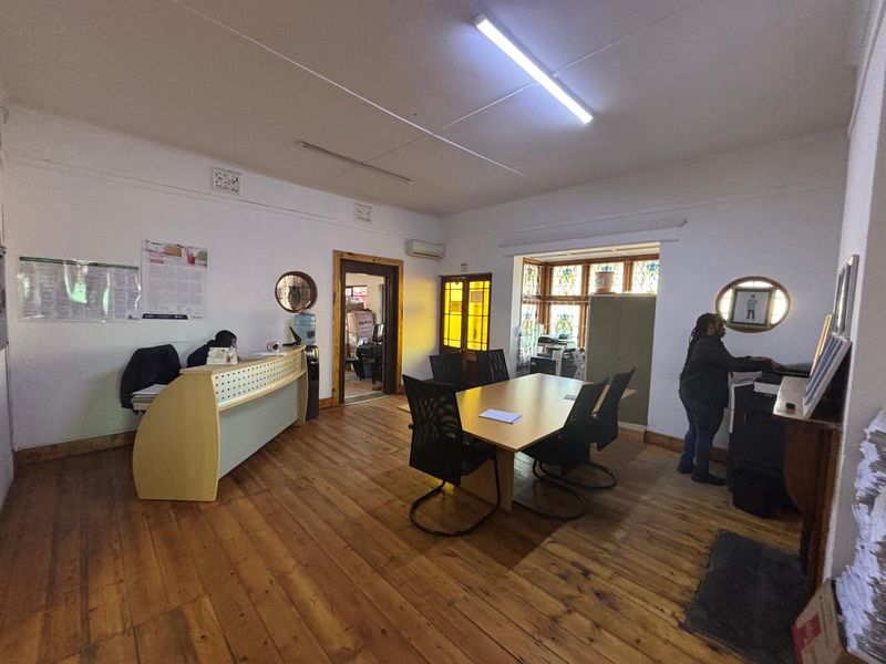 A functional office space featuring original hardwood flooring, stained glass windows, and a built-in reception desk, providing a professional work environment.