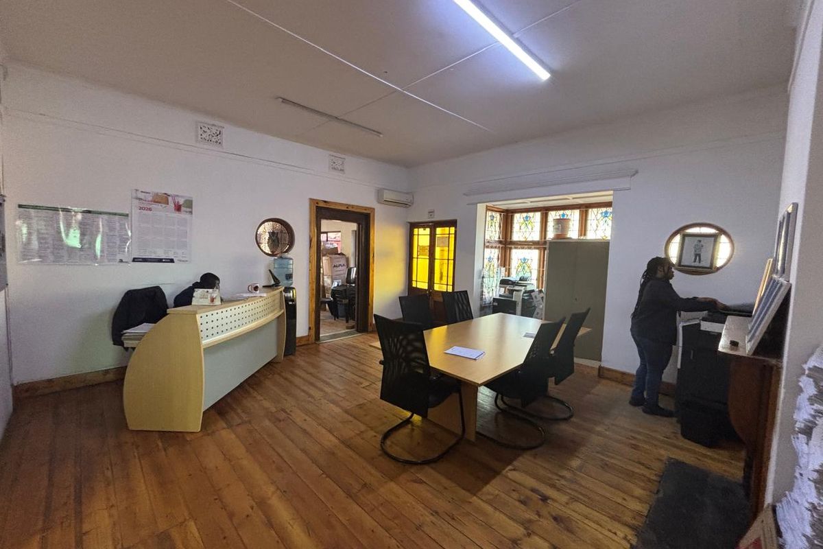 A functional office space featuring original hardwood flooring, stained glass windows, and a built-in reception desk, providing a professional work environment.