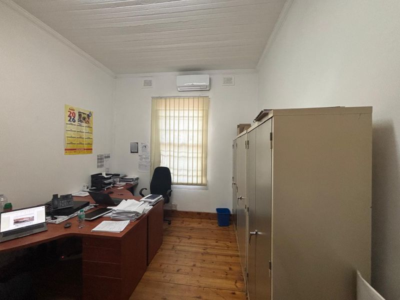 A functional office space featuring timber flooring, a timber ceiling, an air conditioning unit, and built-in metal storage cabinets.