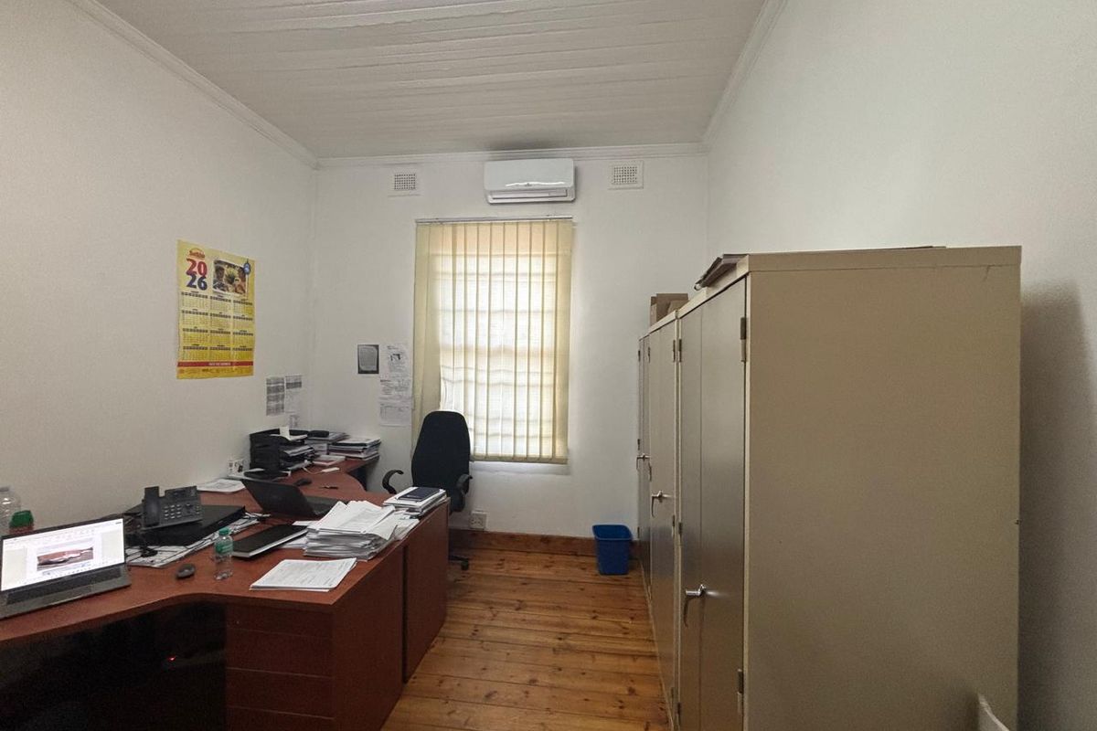 A functional office space featuring timber flooring, a timber ceiling, an air conditioning unit, and built-in metal storage cabinets.
