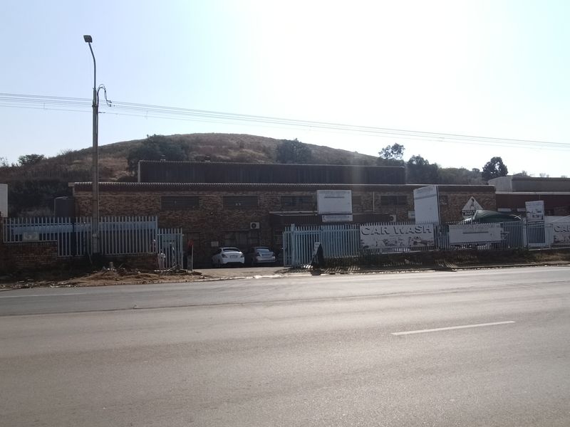 Street-facing view of an industrial property featuring a brick facade, secure perimeter fencing, and gated access points.