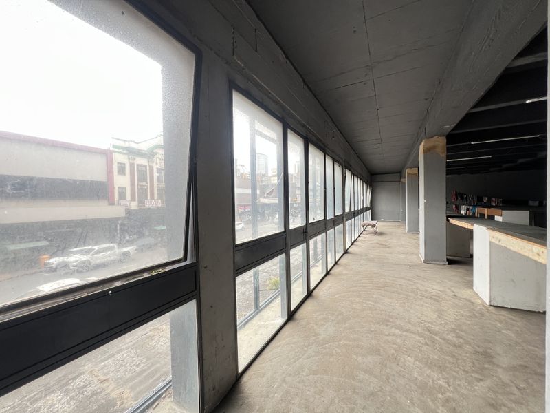 An expansive, unfinished open-plan space featuring large windows, exposed concrete ceilings, and structural columns, offering a blank canvas for custom interior development.