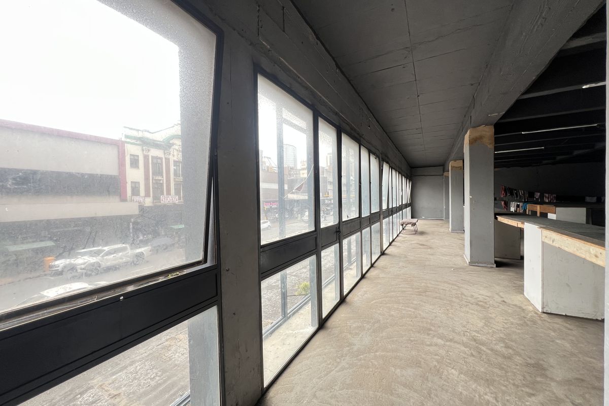 An expansive, unfinished open-plan space featuring large windows, exposed concrete ceilings, and structural columns, offering a blank canvas for custom interior development.