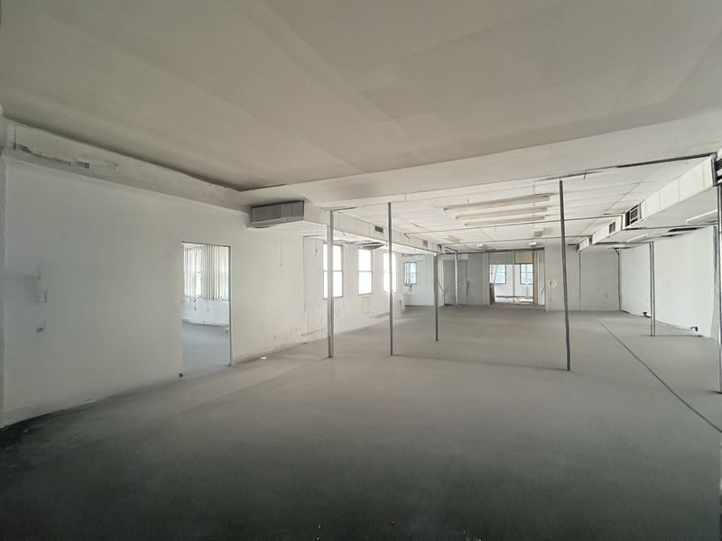 A large, vacant open-plan commercial or residential space featuring exposed ceilings, support columns, and ducted air conditioning, ready for renovation or fit-out.