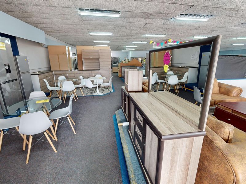 Spacious open-plan commercial showroom area featuring suspended acoustic ceilings, recessed lighting, and fitted kitchen cabinetry displays.