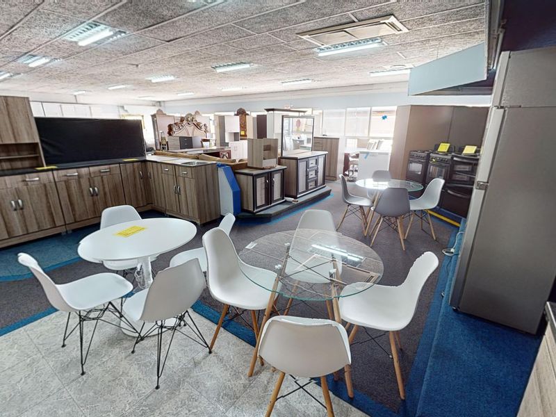 Open-plan commercial showroom space featuring built-in cabinetry, integrated kitchen displays, suspended ceilings, and mixed flooring finishes.