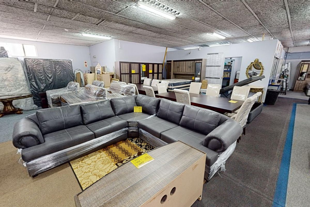 A large open-plan commercial showroom space featuring acoustic ceiling tiles and overhead fluorescent lighting, currently utilized for furniture retail display.