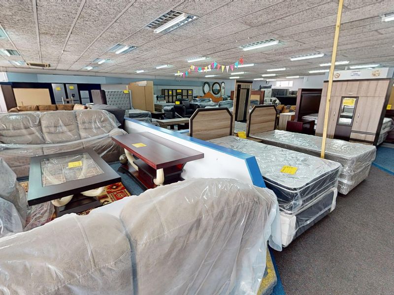 A large commercial showroom space featuring suspended acoustic ceiling tiles, recessed fluorescent lighting, and durable commercial carpeting throughout the open floor plan.