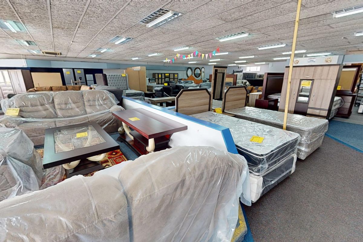 A large commercial showroom space featuring suspended acoustic ceiling tiles, recessed fluorescent lighting, and durable commercial carpeting throughout the open floor plan.