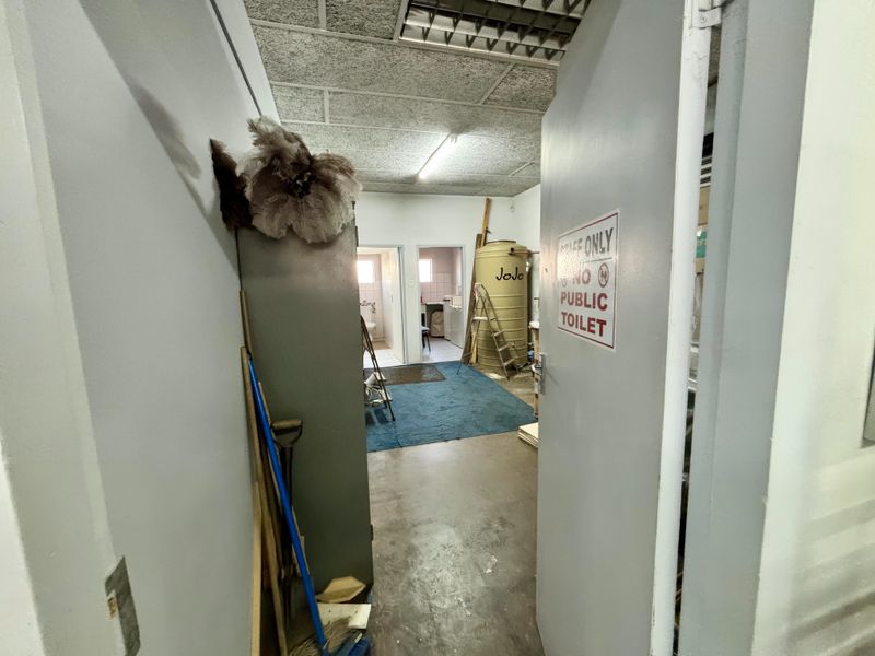 Utility storage area featuring a water tank, concrete flooring, and suspended ceiling, currently used for back-of-house storage.