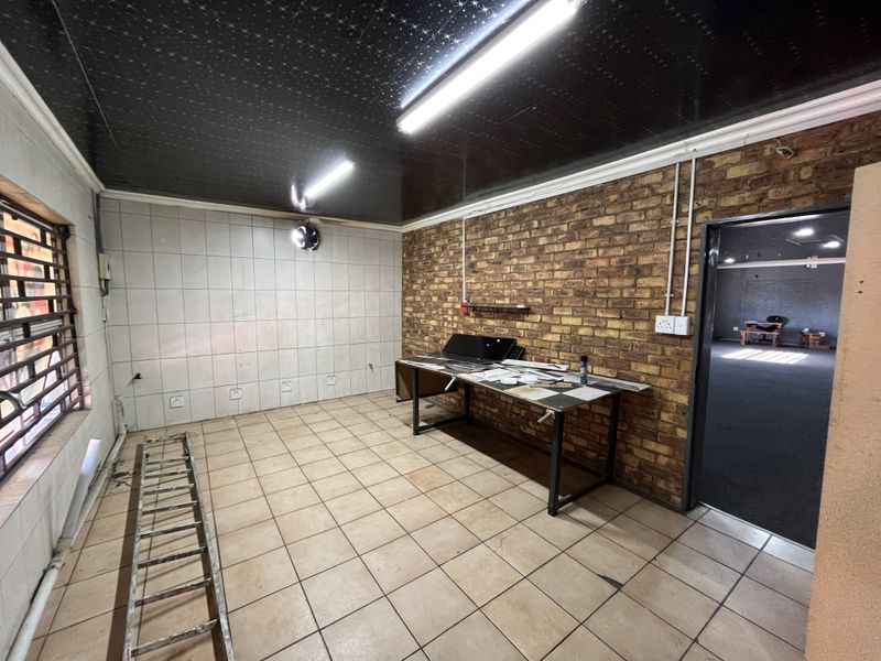 A functional utility space featuring exposed brick walls, tiled flooring, and industrial-style lighting, suitable for various commercial or storage purposes.
