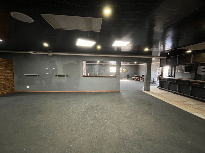 Spacious open-plan retail or commercial area featuring a built-in bar counter, recessed lighting, and a pass-through window, offering a versatile layout for various business uses.