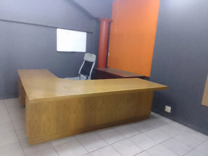 A functional office space featuring tiled flooring, a prominent accent column, and neutral wall finishes, suitable for a professional work environment.