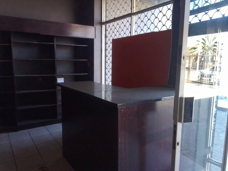 Commercial entry area featuring a built-in reception counter, dark wood shelving units, and security gate access.