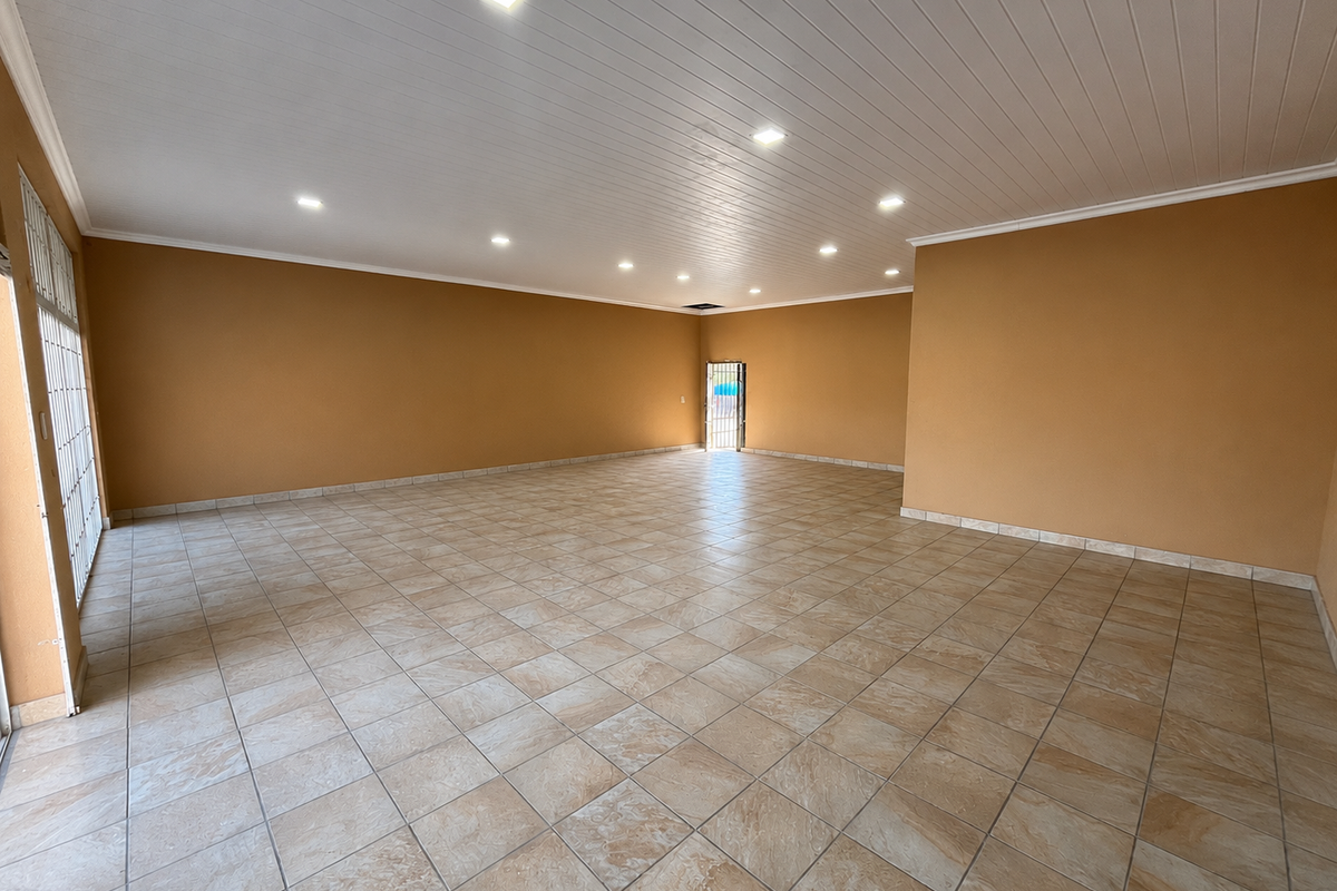 A spacious, empty open-plan retail area featuring neutral walls, tiled flooring, and recessed ceiling lighting, suitable for various commercial business layouts.