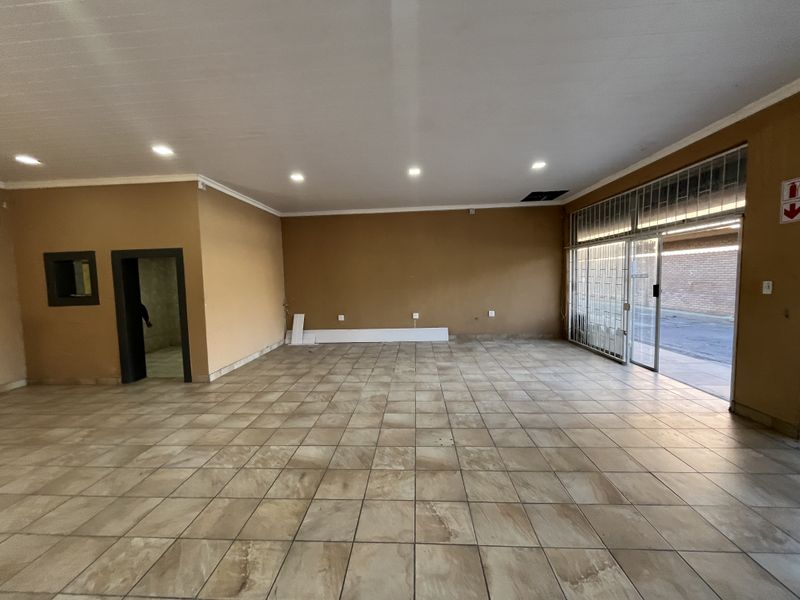 Spacious open-plan retail area featuring tiled flooring, recessed lighting, and a secure glass storefront entrance, suitable for various commercial business applications.