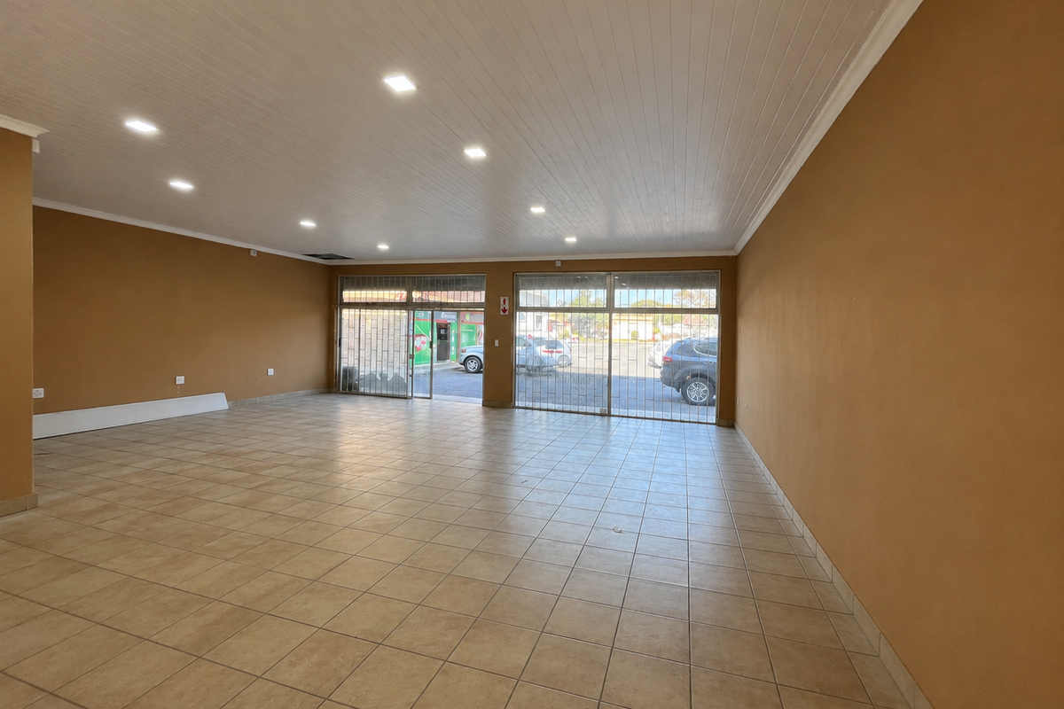 Spacious open-plan retail unit featuring tiled flooring, recessed downlighting, and secure glass storefront access, suitable for various commercial business applications.