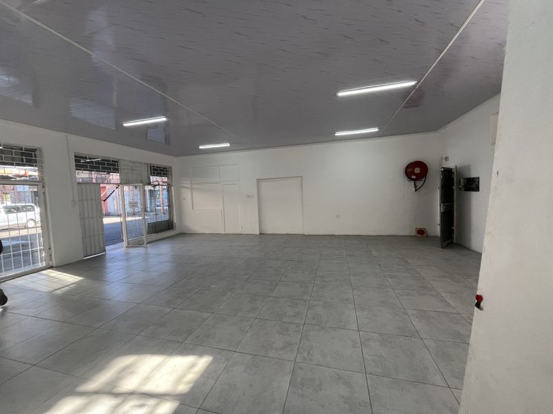 A spacious, open-plan retail unit featuring tiled flooring, a modern suspended ceiling, and large glass storefront windows providing excellent natural light and visibility.