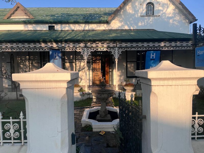 Charming heritage-style business premises featuring a classic veranda with intricate wrought iron detailing, a central stone fountain, and a secure gated entrance.