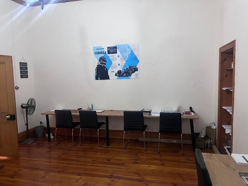 A functional office space featuring polished timber flooring, high ceilings, and built-in shelving, suitable for a professional work environment.