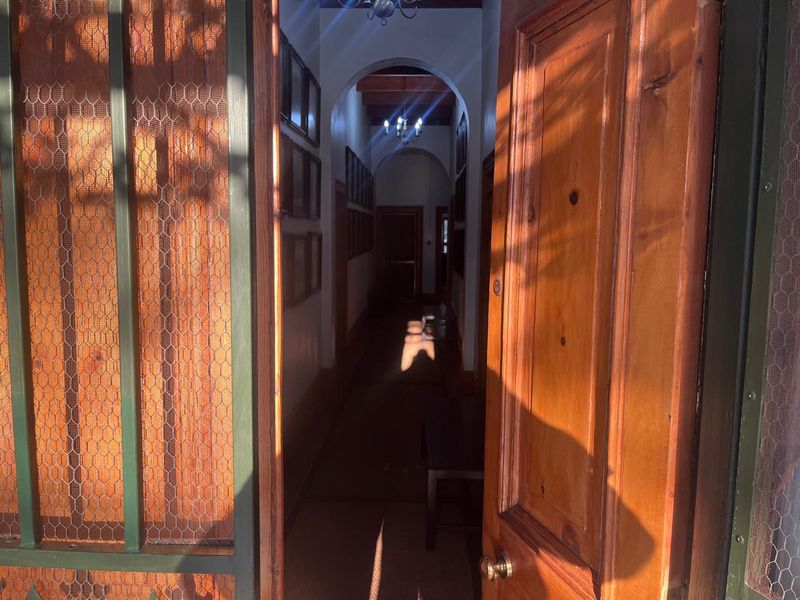 A long, narrow hallway featuring arched architectural details, timber door frames, and traditional ceiling lighting, creating a classic transition space.
