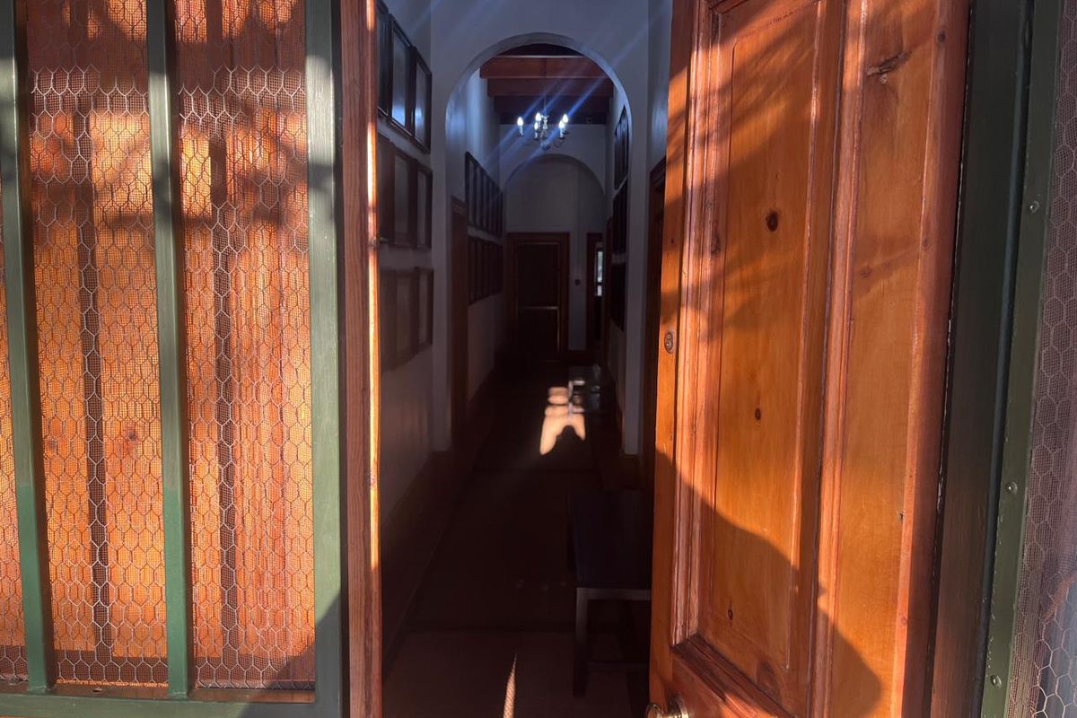 A long, narrow hallway featuring arched architectural details, timber door frames, and traditional ceiling lighting, creating a classic transition space.