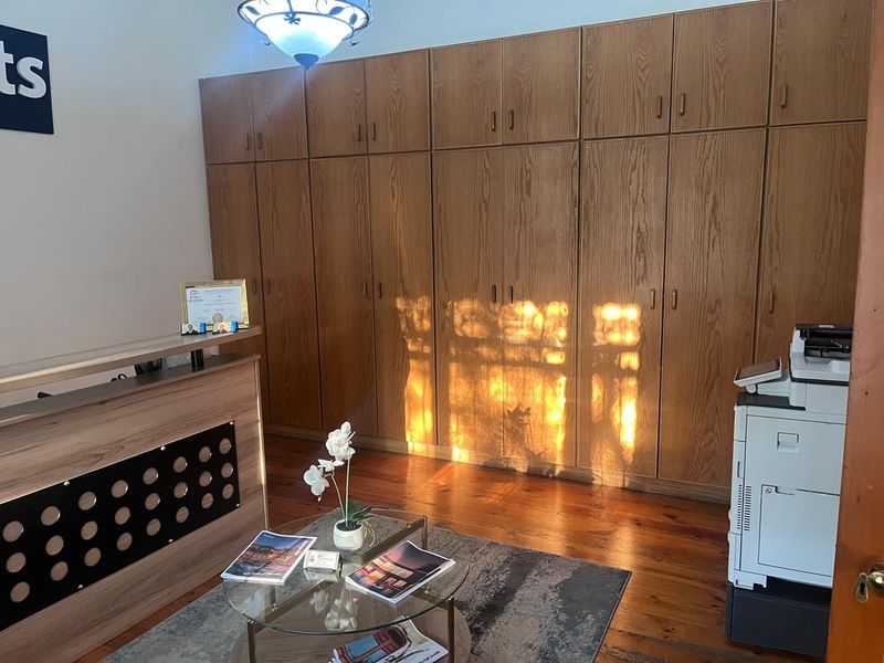 Professional office space featuring extensive built-in wooden cabinetry, polished hardwood flooring, and a dedicated reception area.